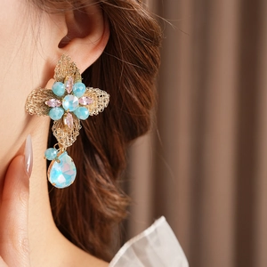 Close-up of vintage flower earrings with blue and pink crystals and a teardrop pendant