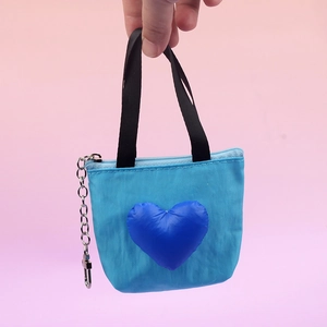 Detail showing the blue mini shopping bag coin purse with a 3D heart and metal keychain