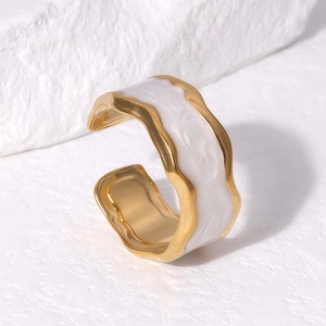 Minimalist gold plated wave open bangle with white marble finish on stone background