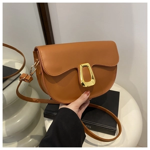 Detail of a brown saddle bag featuring a polished gold geometric buckle and leather strap