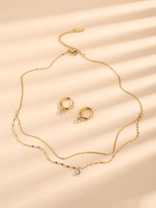 Detail of a gold-plated double-layer necklace and matching stud earrings with clear stones