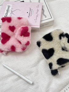 Cute plush heart-patterned coin purses in pink and off-white on a soft fabric