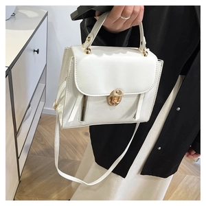 Close-up of structured white leather bag with golden twist lock and rivet details