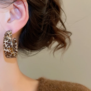 Close-up of leopard print acetate C-shaped hoop earring worn by a model