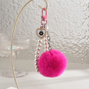 Détail d'un porte-clés en fausse fourrure rose avec chaîne de perles et pendentif cœur