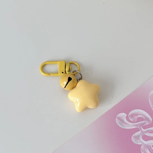 Macro detail of yellow star keychain featuring matching bell and metallic D-ring clasp