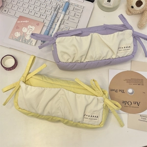 Close-up of pastel purple and yellow fabric pencil cases with decorative bow drawstrings