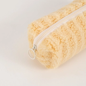 Detail shot of the cream plush pencil case showing soft faux fur texture and ring zipper