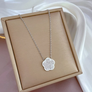 Macro shot of silver flower pendant with clear crystals on a premium jewelry box