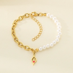 Detail of gold chain and pearl bracelet with a red heart hollow teardrop charm