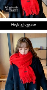 Detail of red cashmere scarf with tassels styled on a black coat for winter warmth