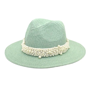 Detail of mint green straw fedora hat with elegant white ribbon and pearl embellishments