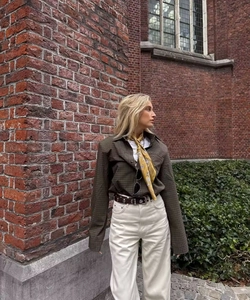 Outdoor street style view of a brown plaid shirt with white pants and a chic neck scarf