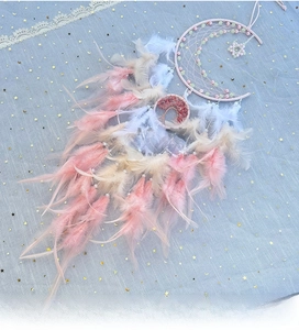Detail of moon-shaped dream catcher with pastel feathers and tree of life stone ornament
