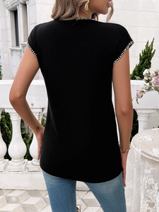 Detail of black knit sweater with white contrast stitching on sleeves and neckline