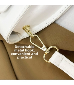 Close-up of white synthetic leather saddle bag with gold metal spring hook hardware