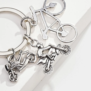Macro detail of silver metal keychains featuring bicycle and motorcycle pendants