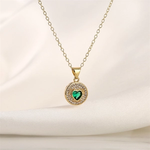 Detailed view of a gold-toned necklace with a green heart zircon in a round pendant