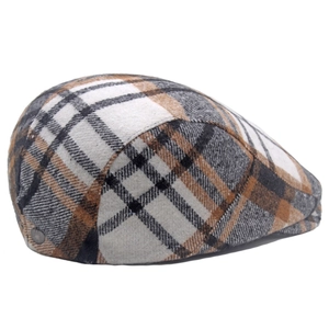 Detail view of the classic brown plaid wool texture and side metal button on the flat cap