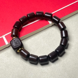 Bracelet en bois de santal foncé avec breloque sculptée et perles dorées d'espacement