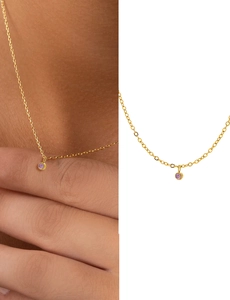 Detail of a minimalist gold necklace featuring a round pink gemstone pendant for women