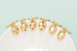 Detailed view of gold oval earrings featuring colorful zircon star inlays on white shell