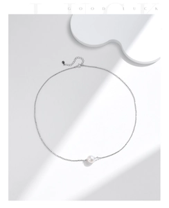 Detailed view of s925 silver beaded chain with a white round pearl pendant on a soft background