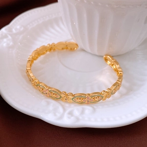 Detailed macro of 18k gold plated enamel floral bangle on vintage ceramic plate