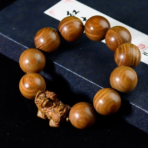 Dettaglio macro di perle in legno di sandalo e Pixiu scolpito su scatola regalo