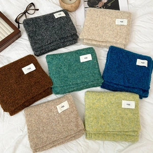 Detail view of colorful knitted bohemian ponchos in various colors with M28 labels