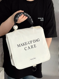 Hanging cosmetic bag featuring white waterproof fabric, carry handle, and pearl detail