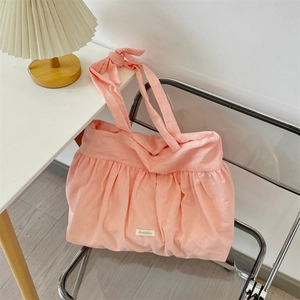 Detail of pink pleated canvas tote bag with bow strap and woven brand tag detail
