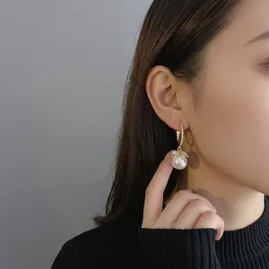 Elegant gold drop earrings featuring luminous pearls and zircon on a female model