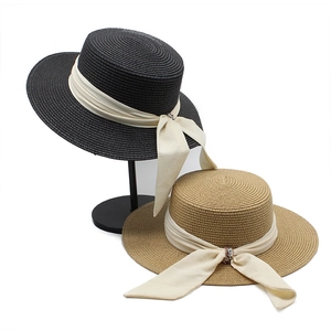 Detailed texture of woven straw boater hat with wide satin ribbon and crystal bow