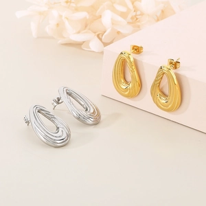 Détail des boucles d'oreilles goutte d'eau en or et argent avec texture ondulée chic