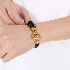 Detail of men's braided leather bracelet featuring a gold horseshoe metal clasp buckle