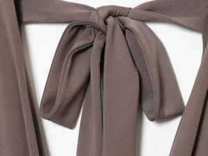 Detail of the tie-knot design and fine knit texture on a dark brown mini dress