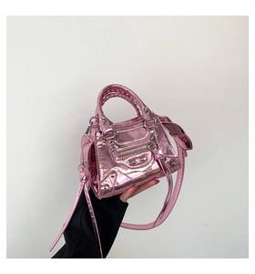 Detail of pink metallic patent leather handbag with rivets and woven handle decoration