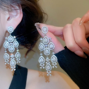 Macro detail of luxury silver fringe earrings with pear-cut zircon and tassel design
