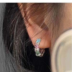 Vue macro de boucles d'oreilles créoles arc-en-ciel en zircon sur modèle avec base en argent