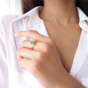 Close-up of gold S925 sterling silver ring with green teardrop zircon gemstones on hand