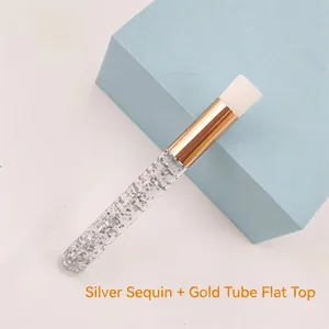 Close-up of flat head makeup brush with silver sequins and golden metal tube
