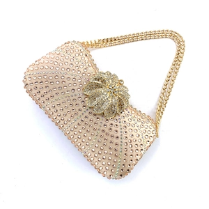 Close-up of champagne rhinestone evening bag with golden floral clasp and chain strap