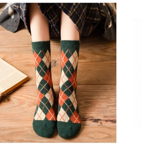 Close-up of vintage argyle pattern wool socks in green and orange on wooden floor