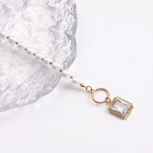 Detail of elegant pearl necklace with golden beads and a sparkling crystal pendant