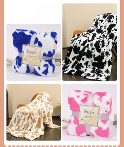 Close-up of soft cow print flannel blankets in blue, black, brown and pink colors