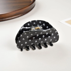 Macro detail of black shark hair claw with white skull print and gold metal spring