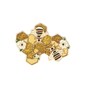Golden enamel bee and honeycomb brooch with yellow glitter and white flower accents