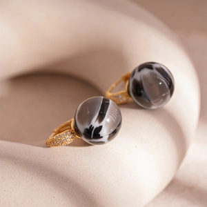 Detail of gold hoops with sparkling zircons and grey marble resin sphere charms