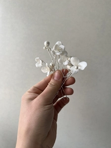 Close-up of white ceramic flower and pearl bridal hair pins with silver metal prongs